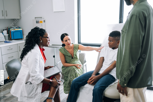 Black doctor consulting mixed race family at local physician practice