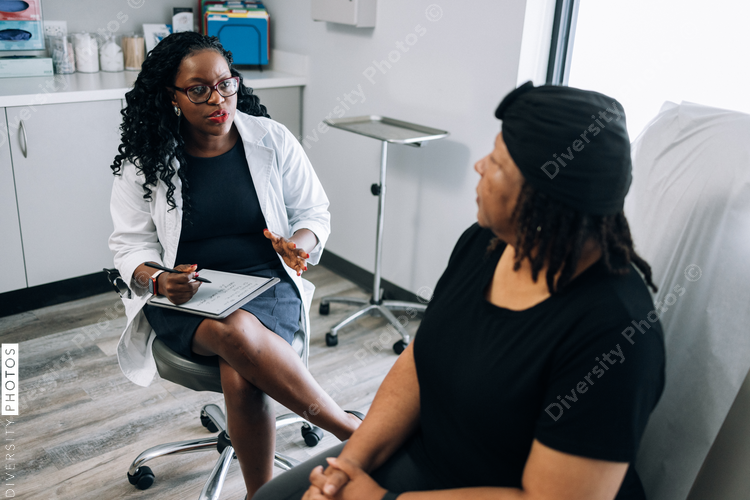 Black female doctor consults woman with head covering