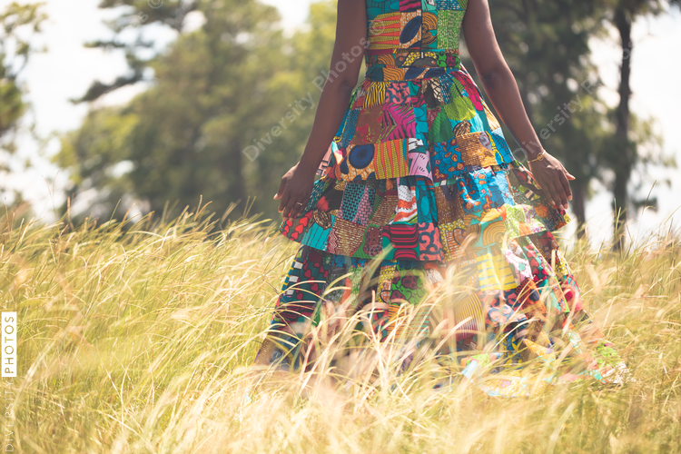 Woman walking through hay field wearing colorful dress