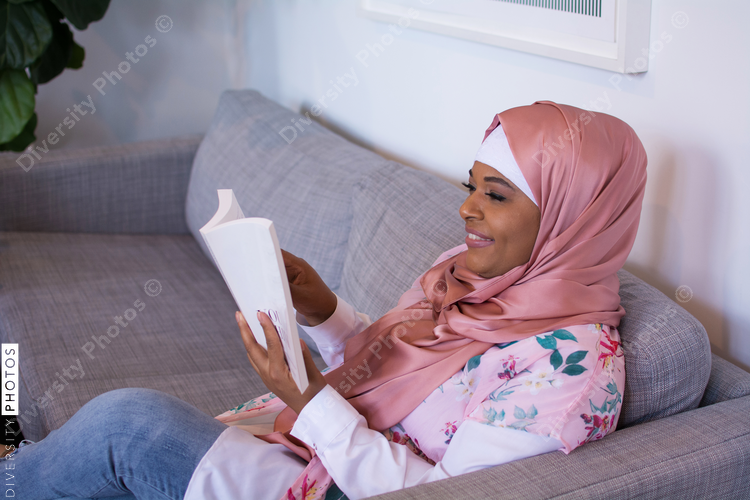 Woman wearing hijab reading on sofa