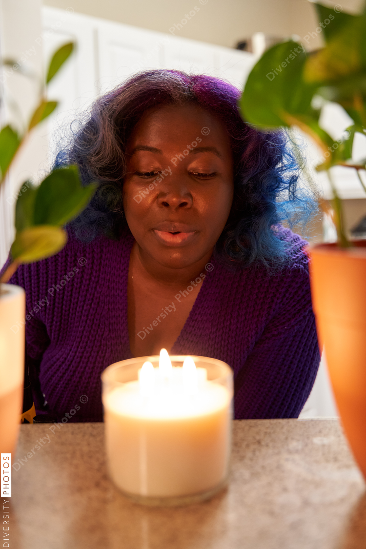 Young Black woman with a candle at home