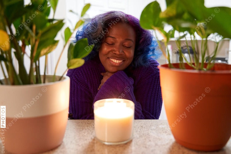 Pleasant young Black woman with a candle at home
