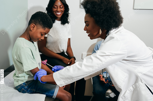 Black doctor examines young boy reflexes