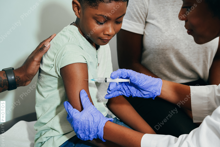 Pediatrician¬†vaccinating her patient, African American