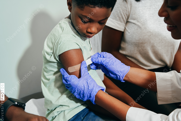 Pediatrician putting adhesive bandage on¬†patients arm