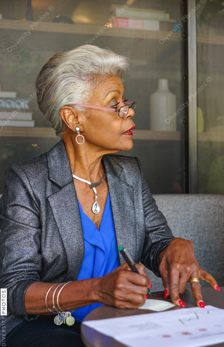 Senior businesswoman writing on paper in office