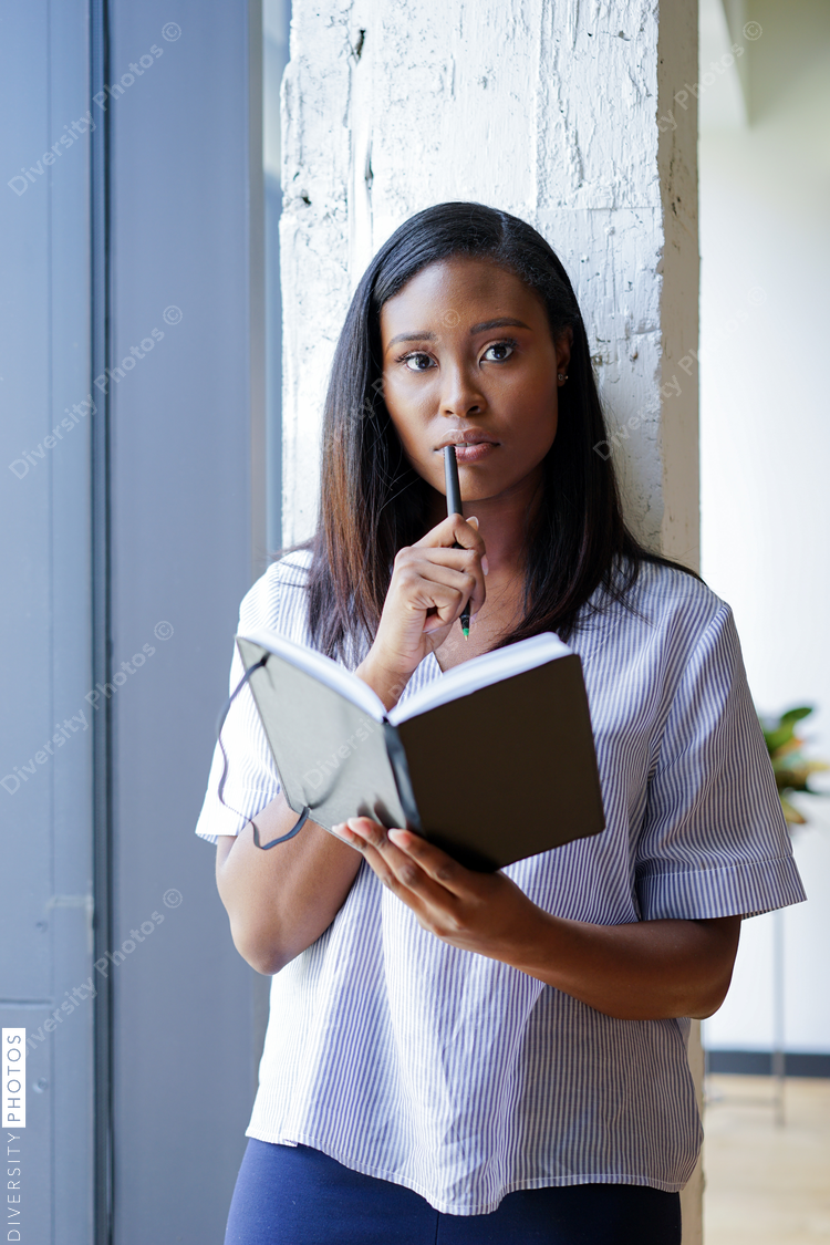 Portrait of businesswoman holding diary while standing near window