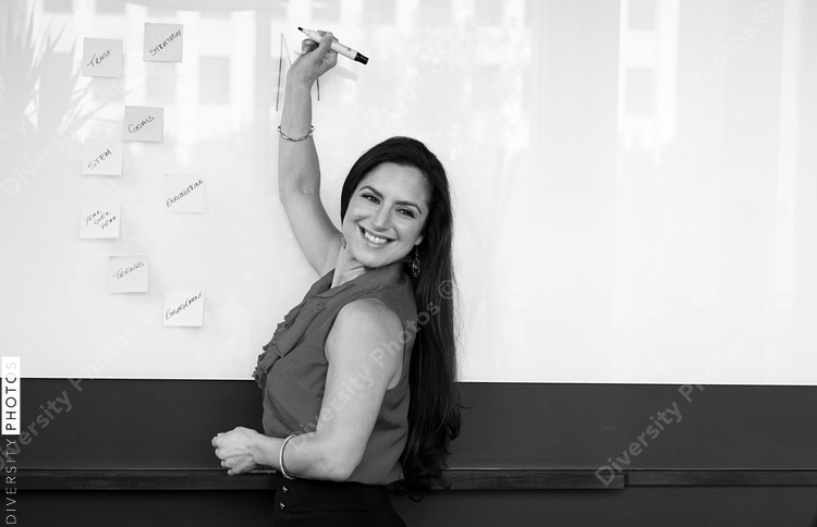 Smiling businesswoman writing on whiteboard in office