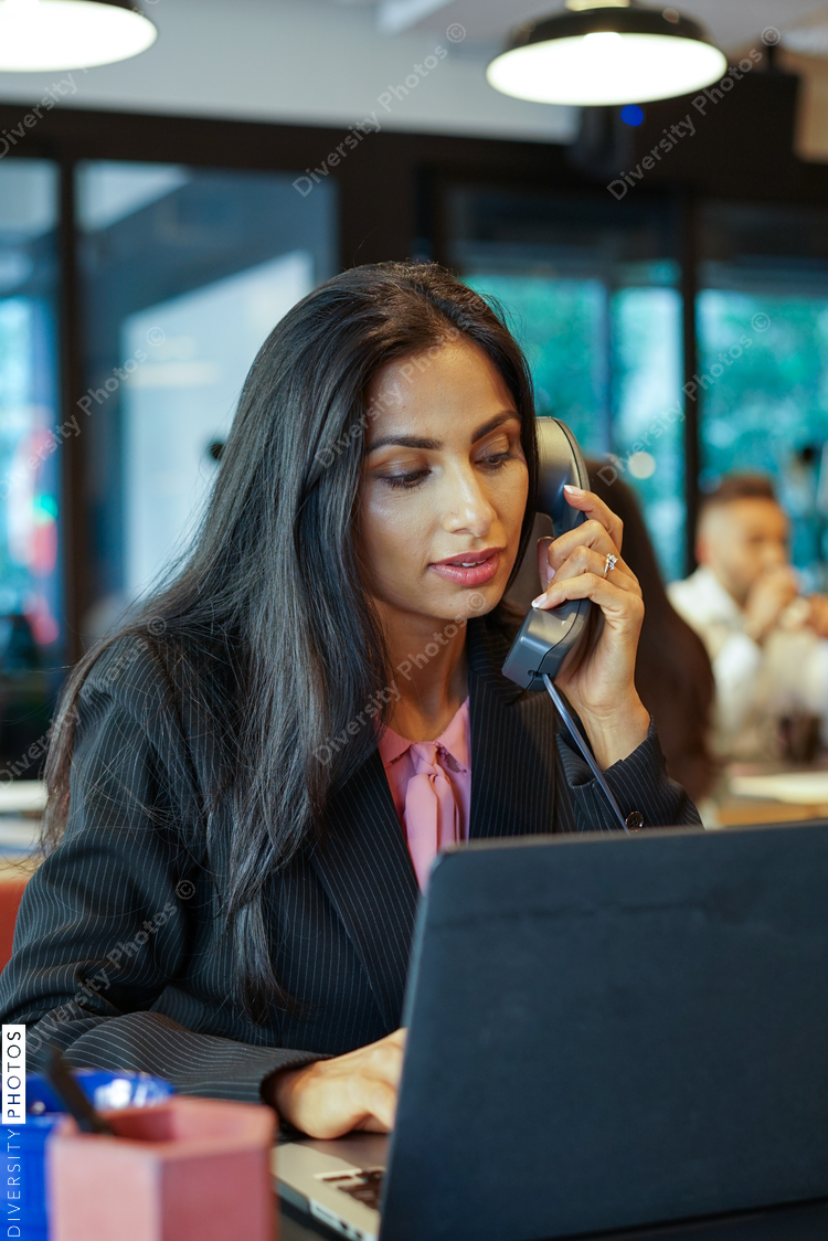 Smiling businesswoman talking on telephone while working on laptop