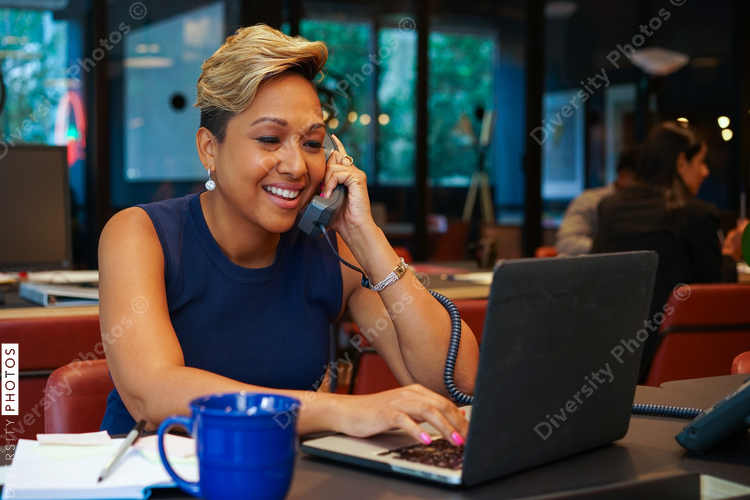 Woman using phone and laptop in office