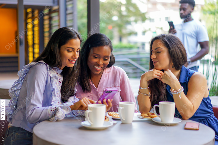 Smiling female friends using smartphone at coffee shop