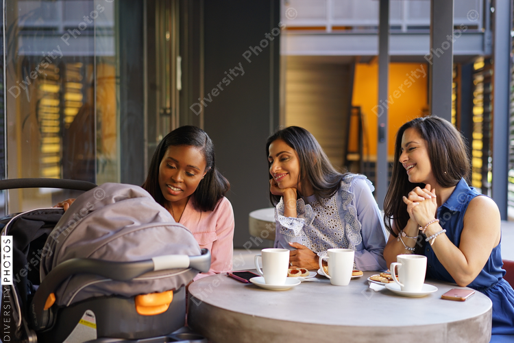 Smiling female friends looking at stroller in coffee shop