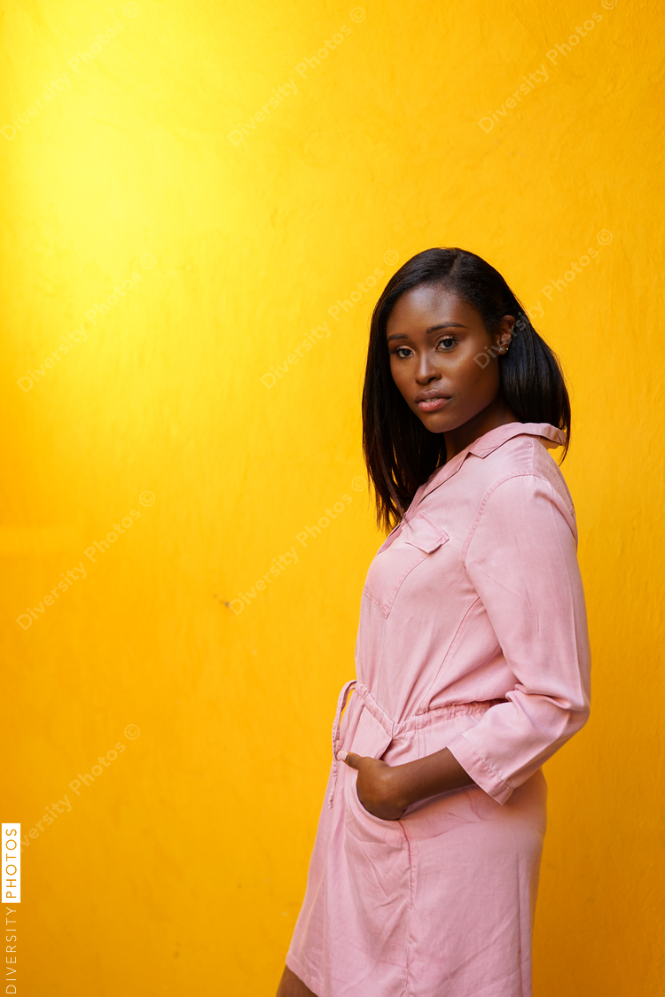 Portrait of young woman standing against yellow background