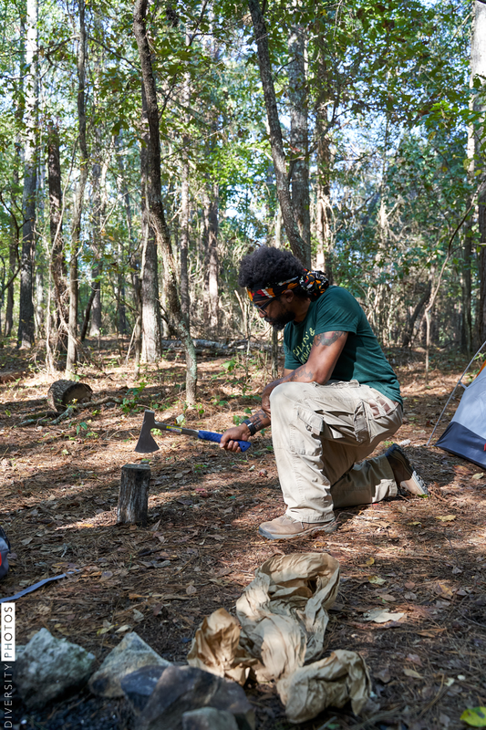 Black man chopping wood for campfire