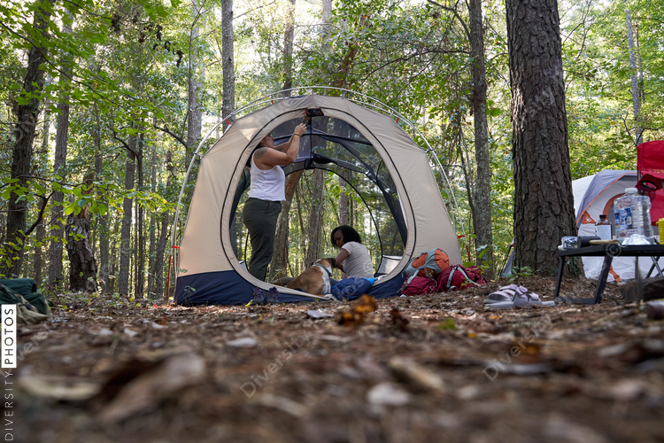 Diverse female friends camping in tent in the woods