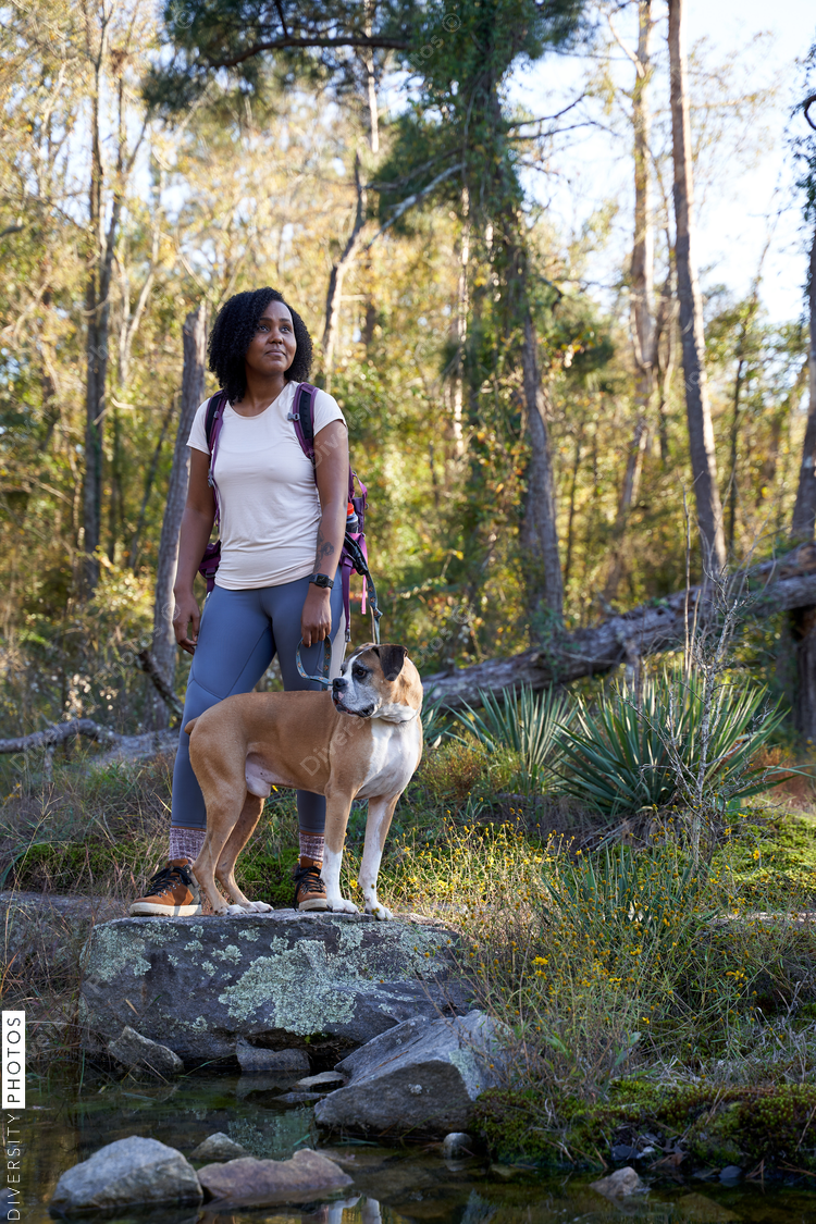 Black woman exploring nature outdoors with pet dog