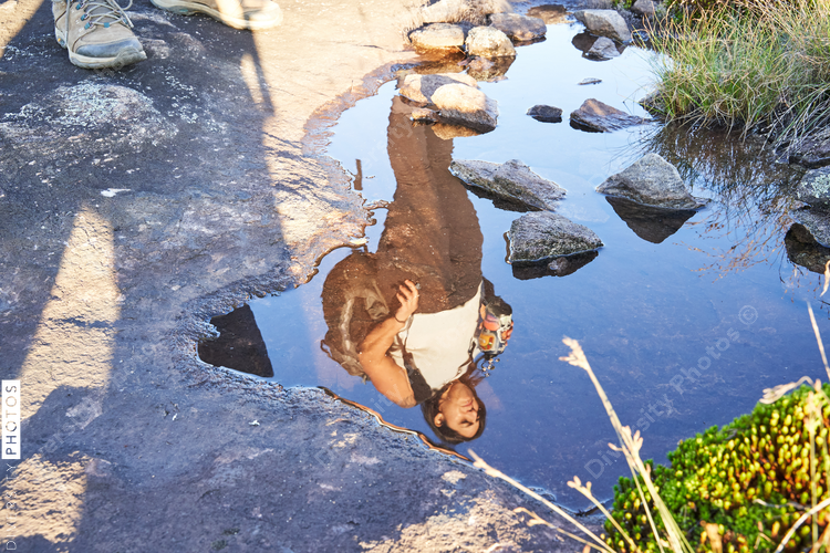 Reflection of Latin woman in water on hike