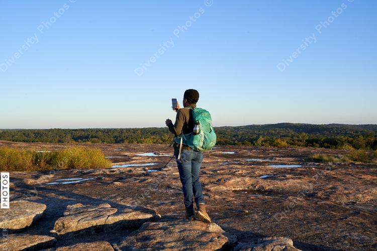 Black woman takes picture of beautiful mountain top view at sunset