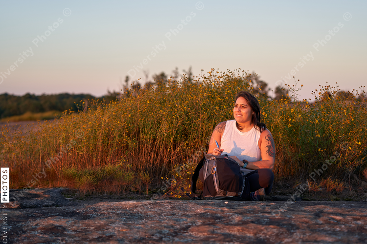 Hispanic woman writing in journal in nature