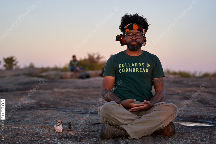 Black man meditates on mountain outdoors