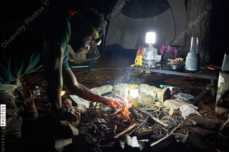 Man lights campfire at campsite at night