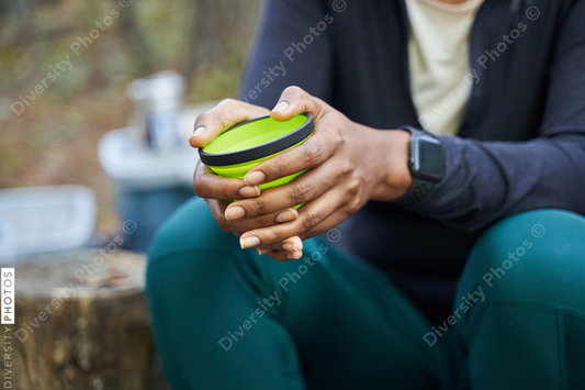 Black hands holding mug at campsite