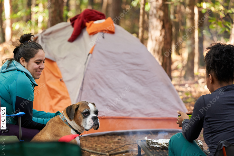 Friends enjoying weekend getaway, relaxing at campsite in woods