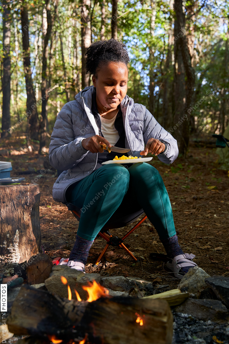 Woman dicing vegetables for breakfast at campsite