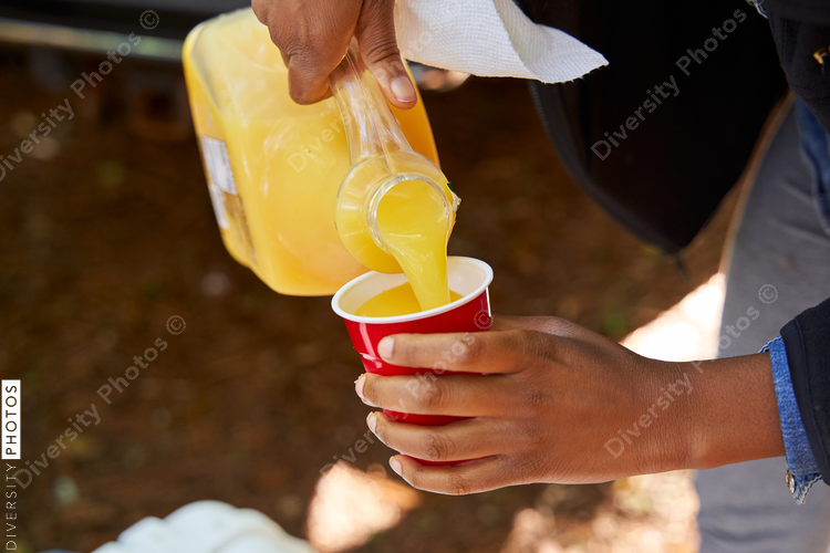 Woman pours orange juice in cup