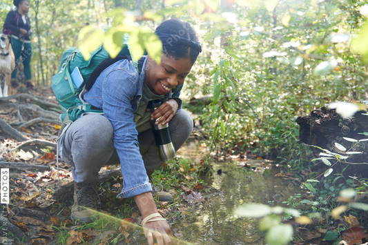 Black female botanist examines plants on trail