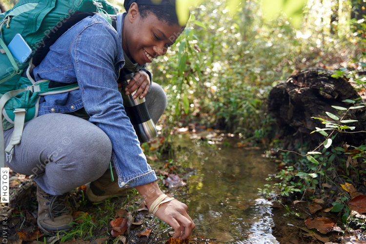 Black female botanist examines plants on trail