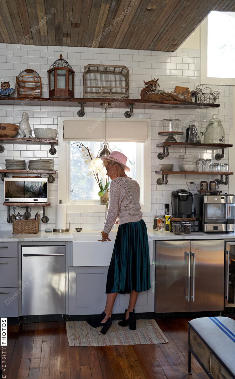 Black woman washing dishes in kitchen at home
