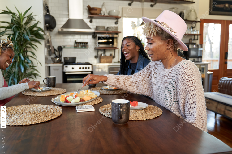 Black girlfriends talking and eating at table, friends togetherness