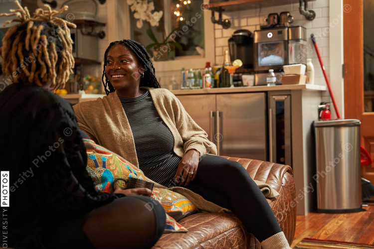 Black girlfriends talking at home during cozy self care retreat