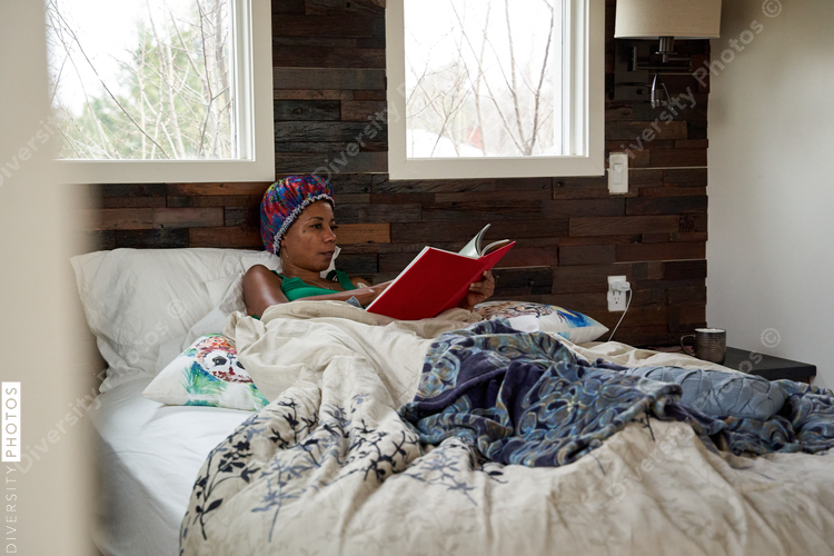 African American woman reading book in bed