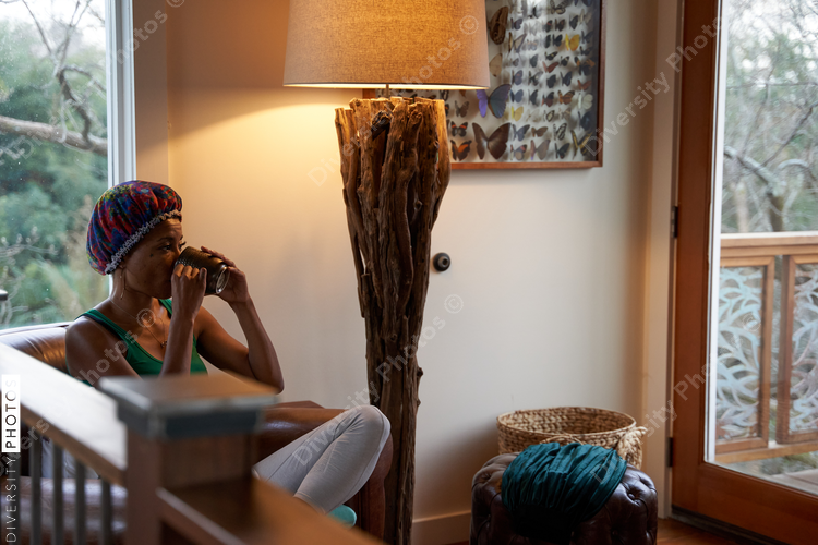 Black woman drinks tea while meditating at home in the morning