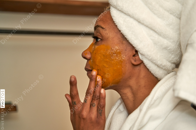 Black woman puts on DIY facial mask, skincare self care