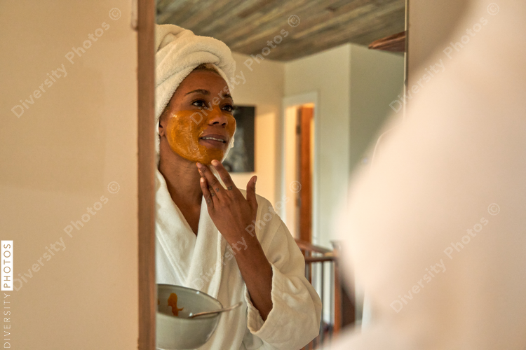 Black woman puts on DIY facial mask, skincare self care