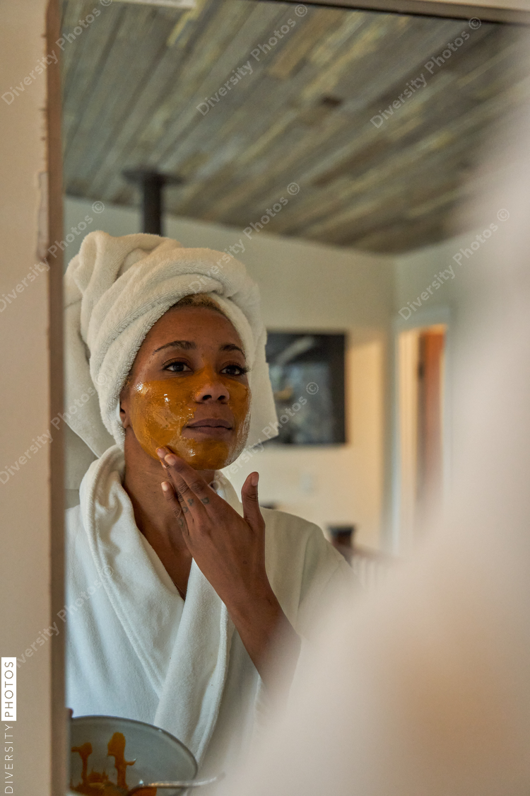 Black woman puts on DIY facial mask, skincare self care