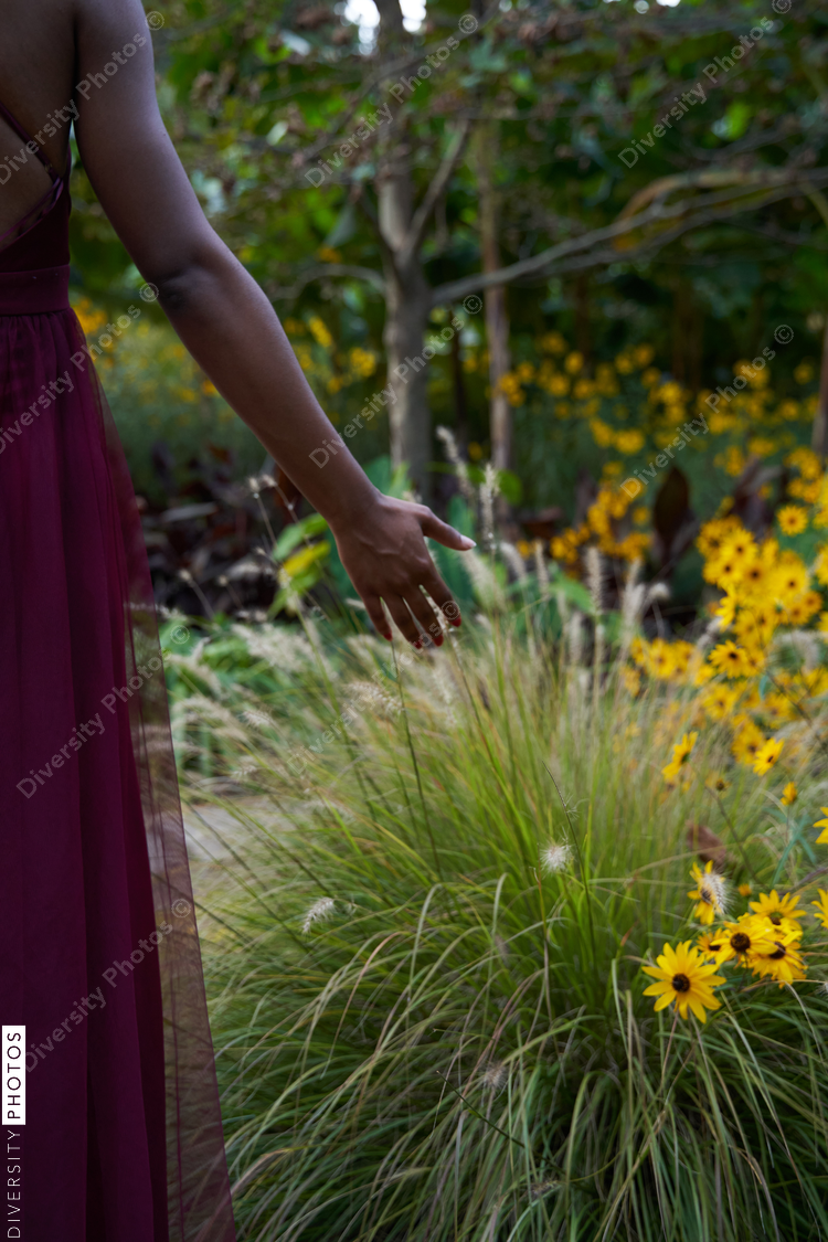 Black woman runs hand through flower field