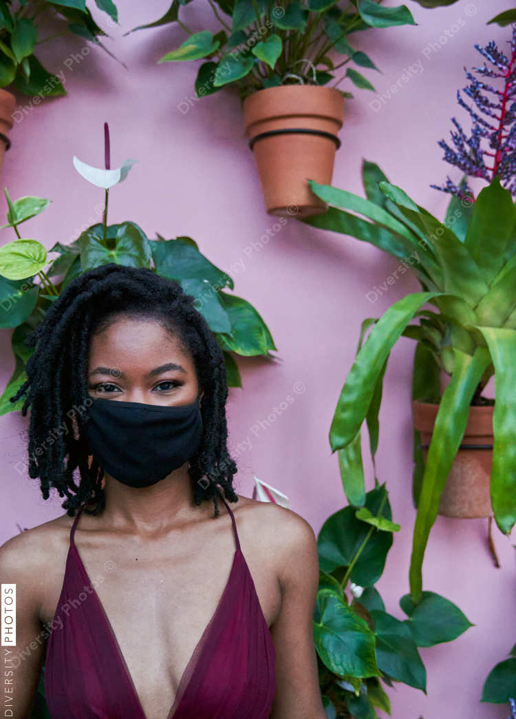 Black woman portrait with plant wall in background, copy space