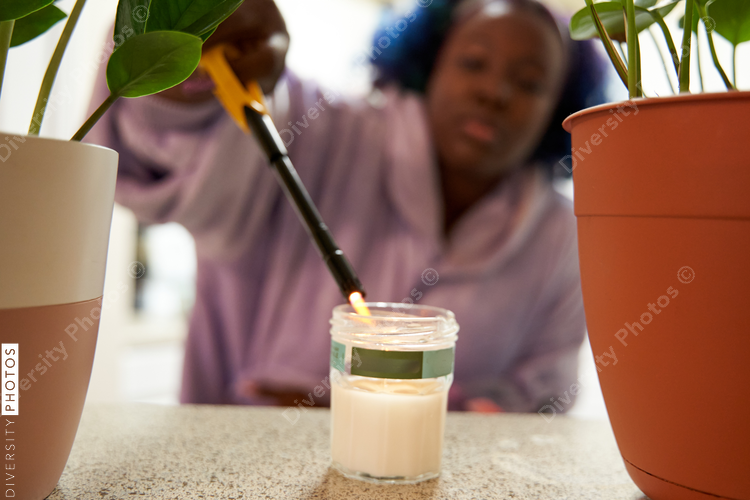 African American woman lighting scented candle at home