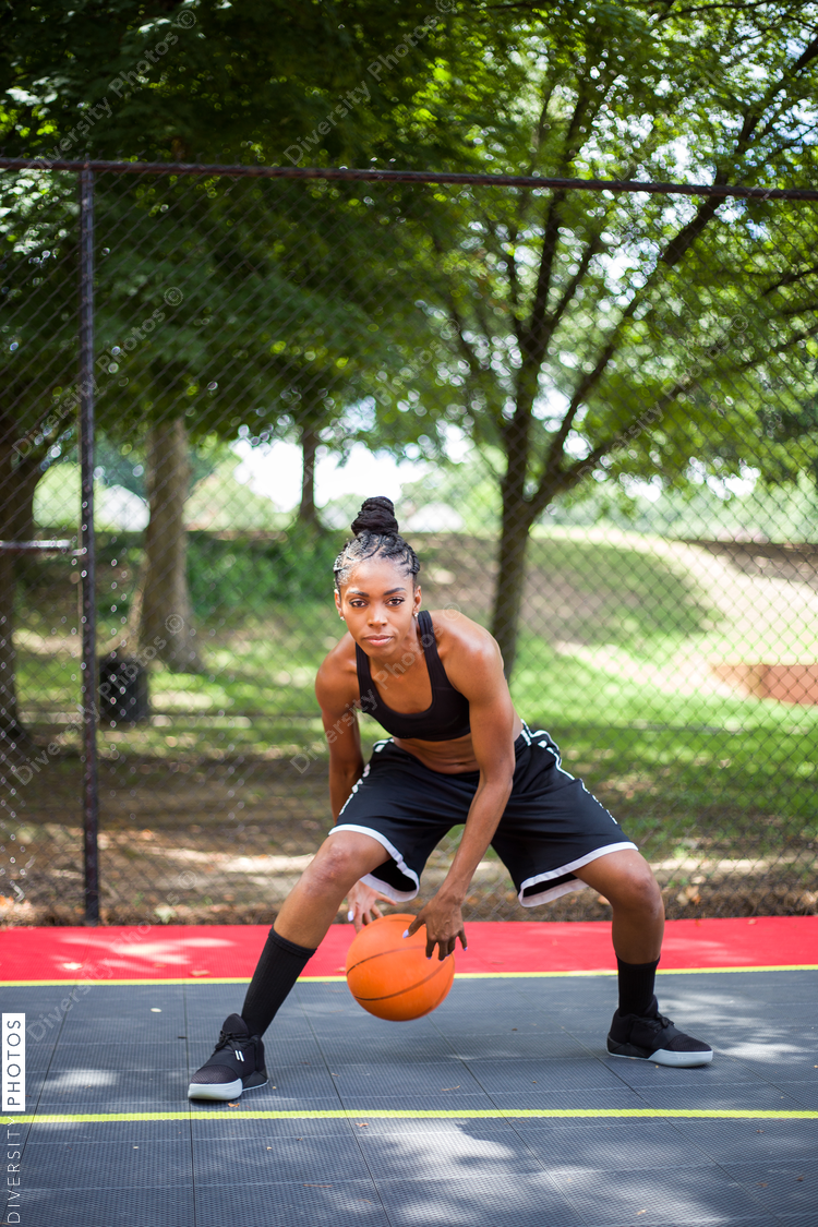 Woman bends forward as she plays basketball