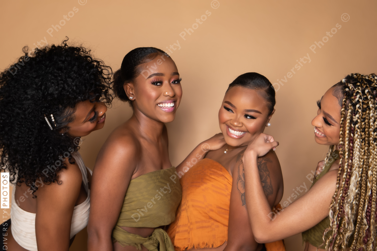 Studio portrait of four beautiful black female friends laughing