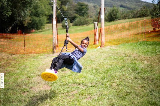 Young black girl playing outdoors on homemade swing
