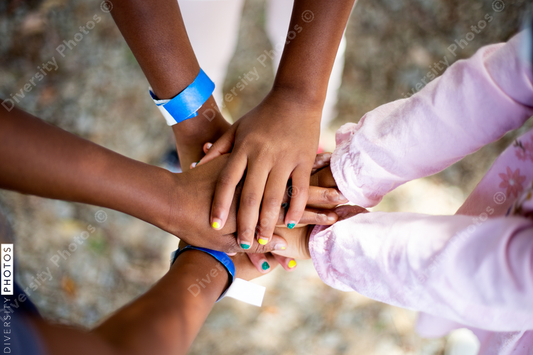 Black kids stacking hands together outdoors in park