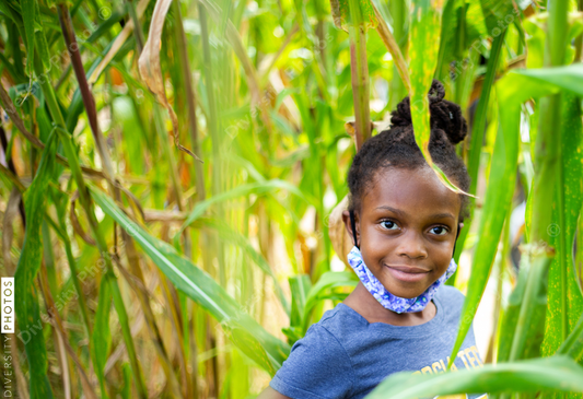 Young girl playing in cornfield outdoors