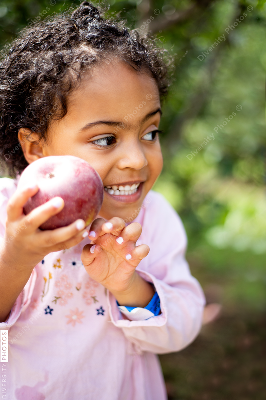 Young girl picking apple on farm