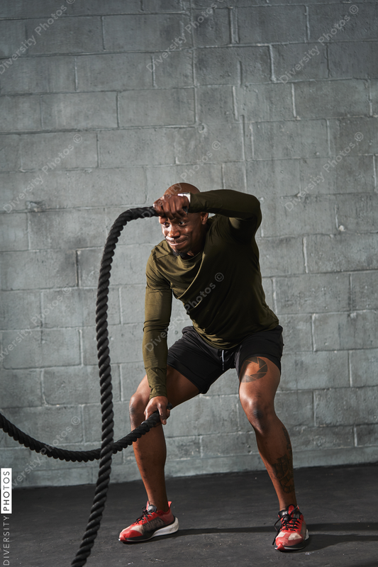 Black man training with battle ropes in crossfit