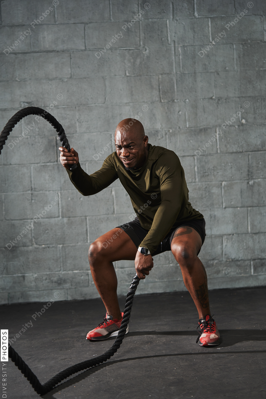 Black man training with battle ropes in crossfit